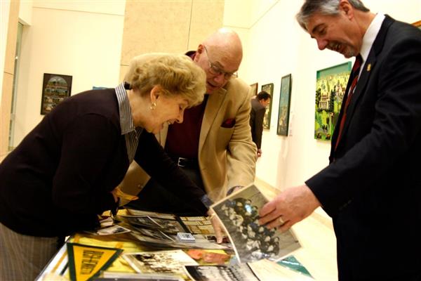 Alumni Terry Mathews-DeSant , Bob Thompson, and Joe Bellanca look at memorabilia at an alumni council event.